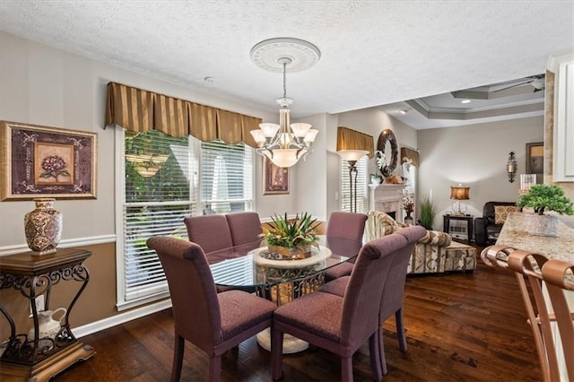 dining space with a chandelier, dark wood finished floors, a textured ceiling, baseboards, and ornamental molding