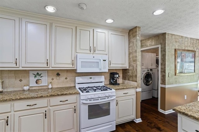 kitchen featuring white appliances, dark wood finished floors, washing machine and clothes dryer, baseboards, and decorative backsplash