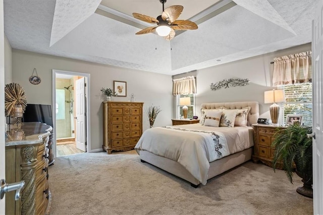 bedroom with carpet floors, multiple windows, ensuite bathroom, and a tray ceiling