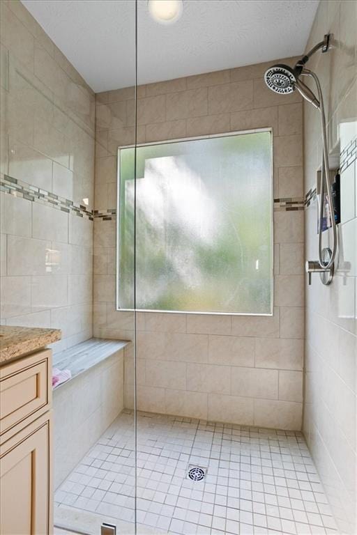 bathroom featuring plenty of natural light, tiled shower, vanity, and tile patterned floors
