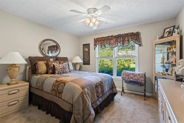bedroom featuring light carpet, a textured ceiling, baseboards, and a ceiling fan