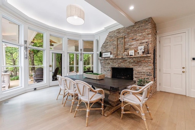 dining area with a wealth of natural light, light wood finished floors, and a fireplace