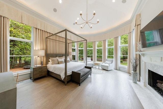 bedroom featuring ornamental molding, a fireplace, multiple windows, and a notable chandelier