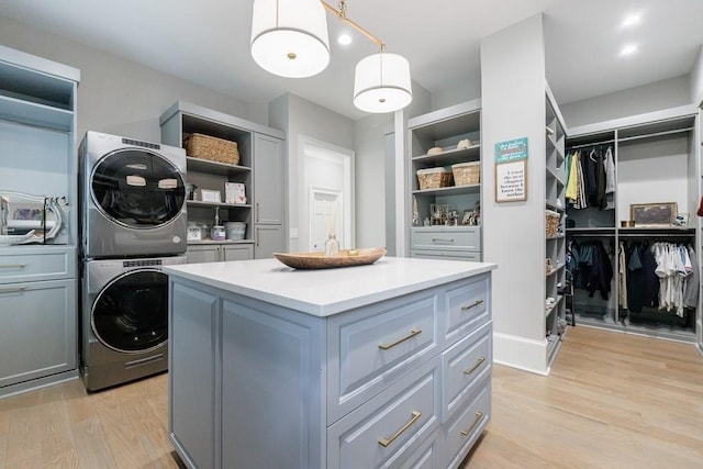 spacious closet with stacked washing maching and dryer and light wood-style floors