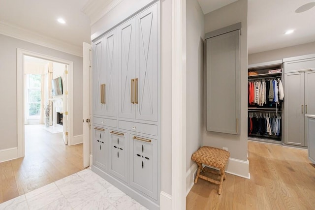 hallway featuring light wood-style floors, baseboards, ornamental molding, and recessed lighting