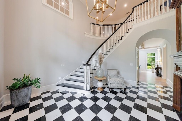 interior space featuring a towering ceiling, baseboards, stairway, tile patterned floors, and arched walkways
