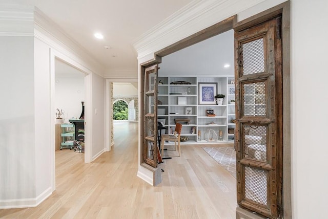 hallway with crown molding, baseboards, and light wood-style flooring