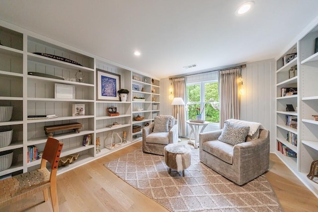 living area with built in features, wood finished floors, and visible vents