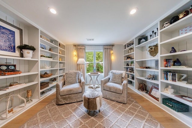 sitting room with visible vents, wood finished floors, and built in shelves