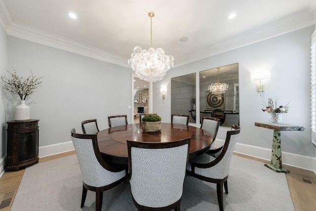 dining room featuring baseboards, a notable chandelier, ornamental molding, and light wood-style floors