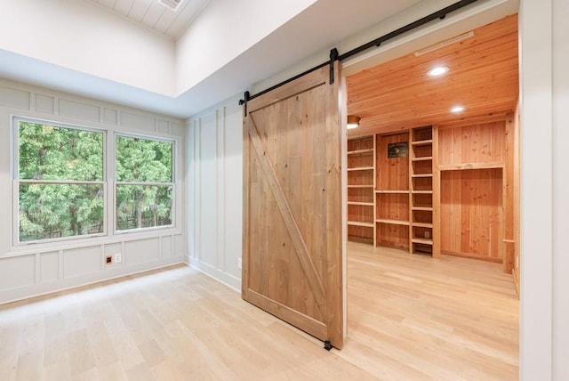 spare room featuring a barn door, wood finished floors, and a decorative wall