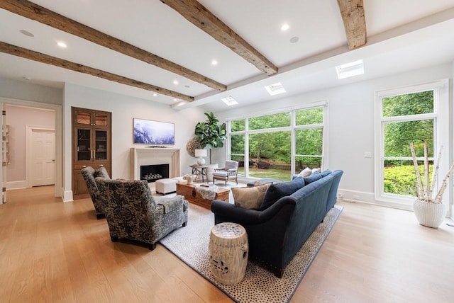 living area featuring a fireplace, beam ceiling, and light wood-type flooring