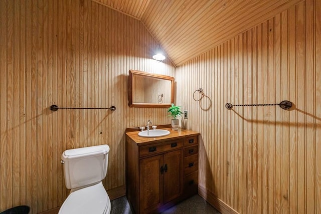 bathroom with vanity, toilet, wooden walls, wooden ceiling, and vaulted ceiling