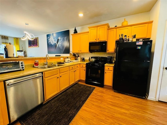 kitchen featuring black appliances, tasteful backsplash, pendant lighting, sink, and light hardwood / wood-style floors