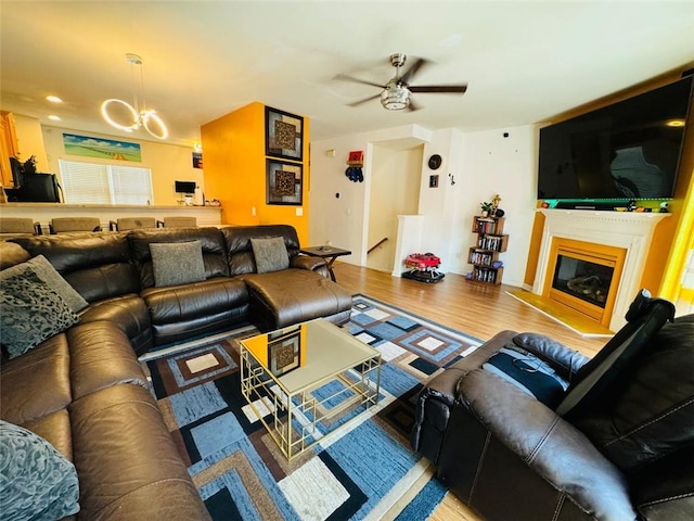 living room featuring ceiling fan with notable chandelier and hardwood / wood-style floors