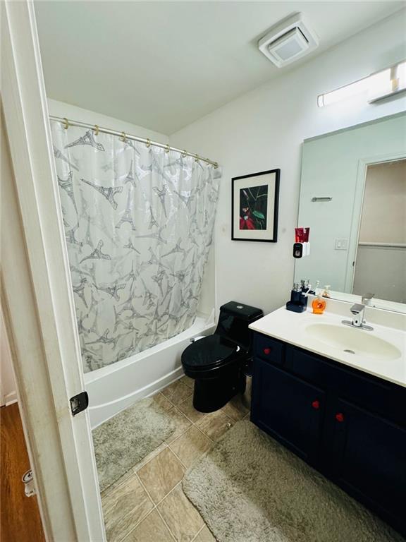 full bathroom with shower / tub combo, tile patterned floors, toilet, and vanity