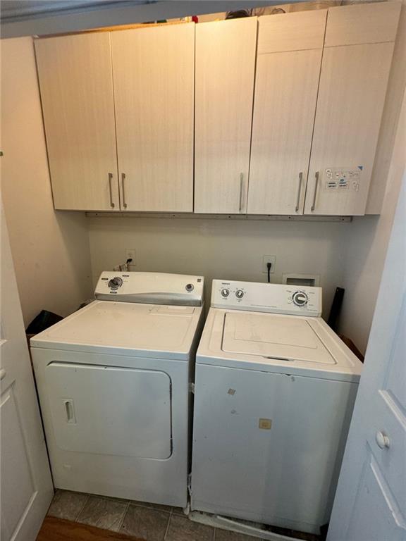 clothes washing area with cabinets, tile patterned floors, and washer and clothes dryer