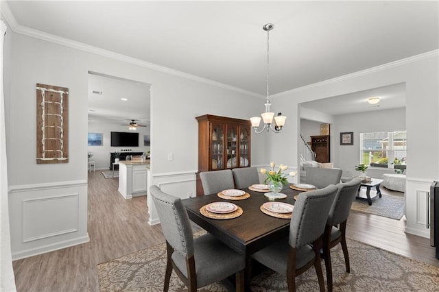 34 Hemlock Gln, Dallas, GA 30132 - dining room with light wood-style floors, a chandelier, ornamental molding, ceiling fan, and stairs