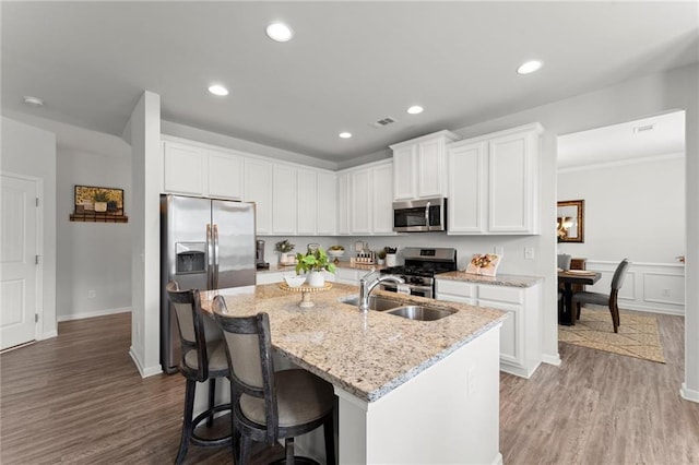 34 Hemlock Gln, Dallas, GA 30132 - kitchen with appliances with stainless steel finishes, a kitchen island with sink, white cabinets, light stone countertops, and recessed lighting