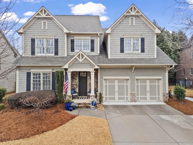 craftsman-style home featuring a garage, stone siding, concrete driveway, and roof with shingles