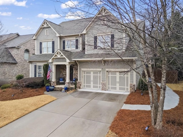 view of front of home with driveway, stone siding, and an attached garage