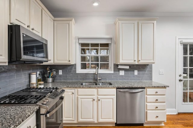 kitchen with a sink, crown molding, stone counters, and stainless steel appliances