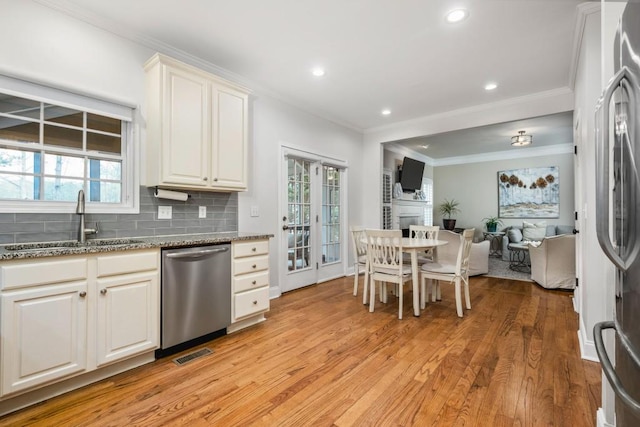 kitchen featuring visible vents, a fireplace, a sink, decorative backsplash, and appliances with stainless steel finishes