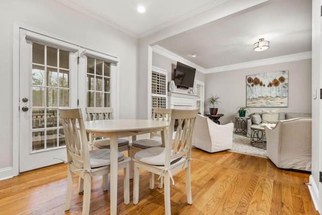 dining area with crown molding, a fireplace, and light wood finished floors