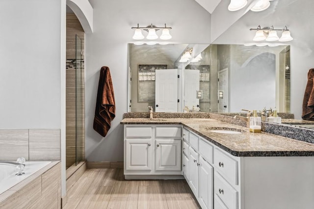 bathroom with double vanity, tiled shower, tiled tub, and a sink