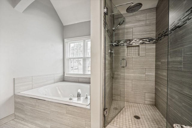 full bathroom featuring a stall shower, a garden tub, and vaulted ceiling