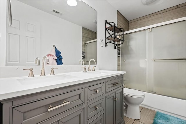 bathroom with double vanity, visible vents, toilet, and a sink