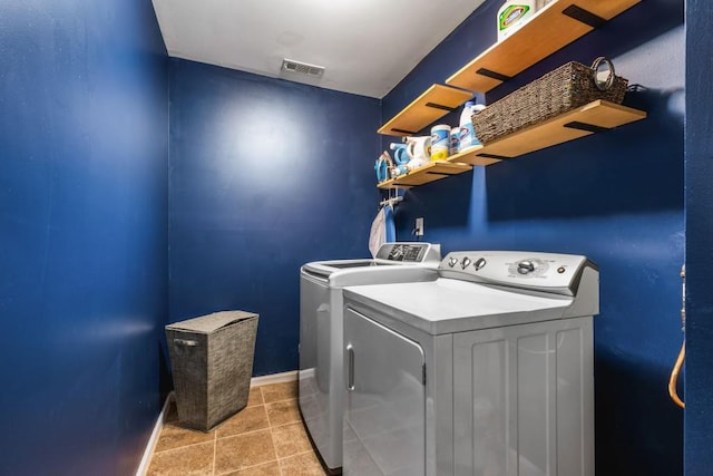 clothes washing area with visible vents, light tile patterned flooring, washing machine and dryer, and laundry area