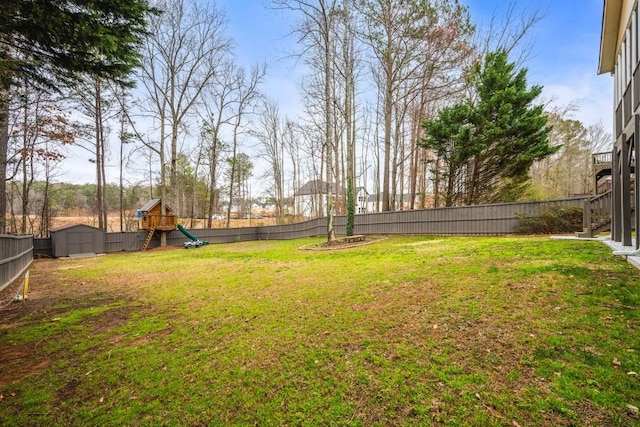 view of yard with an outbuilding, a playground, a fenced backyard, and a shed