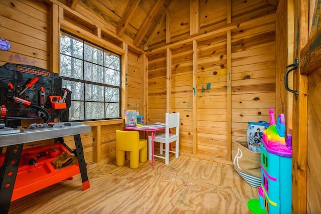 playroom featuring wood walls and lofted ceiling