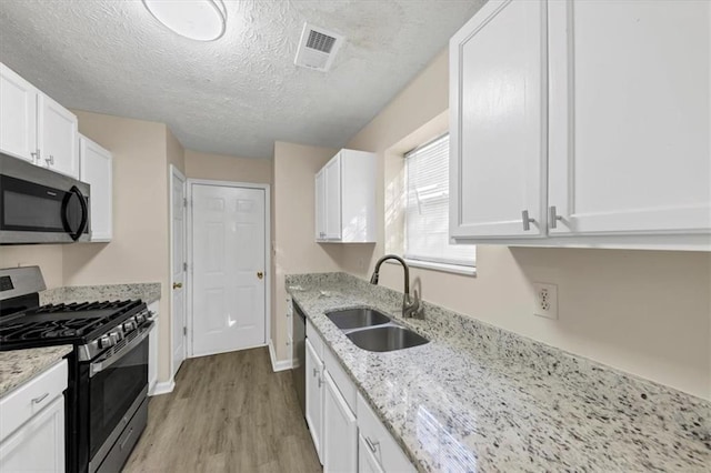 kitchen with light hardwood / wood-style floors, white cabinetry, sink, and appliances with stainless steel finishes