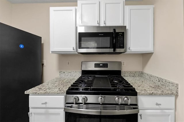 kitchen with white cabinets, stainless steel appliances, and light stone counters