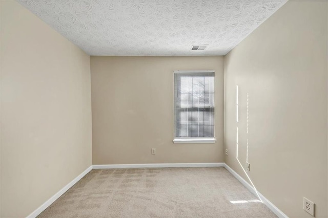unfurnished room with light colored carpet and a textured ceiling