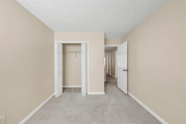 unfurnished bedroom with light carpet, a closet, and a textured ceiling
