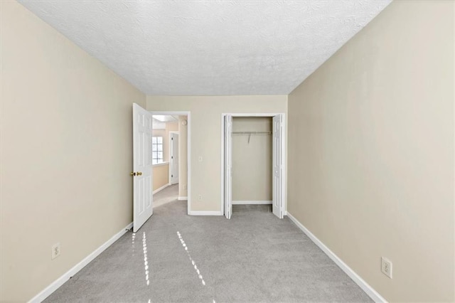 unfurnished bedroom featuring a textured ceiling, light carpet, and a closet