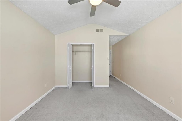 unfurnished bedroom featuring lofted ceiling, ceiling fan, light colored carpet, and a textured ceiling