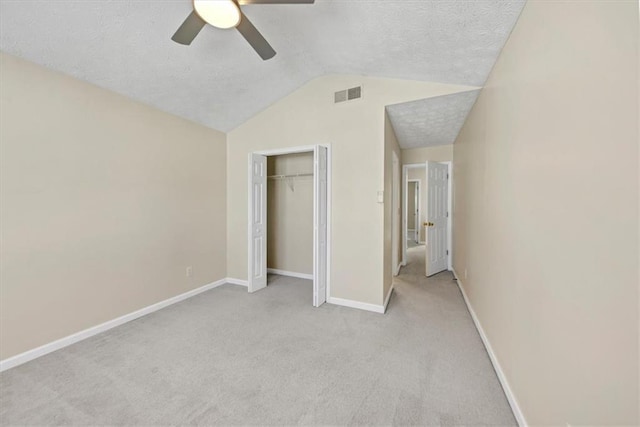 unfurnished bedroom with ceiling fan, a closet, light carpet, and lofted ceiling