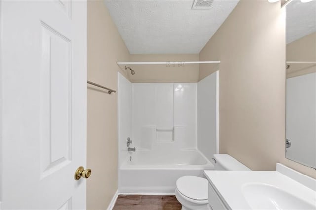 full bathroom with hardwood / wood-style floors, vanity, bathing tub / shower combination, toilet, and a textured ceiling