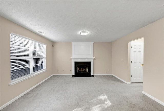 unfurnished living room featuring a textured ceiling, a large fireplace, and light carpet