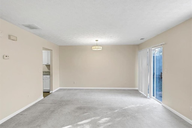 carpeted empty room featuring a textured ceiling
