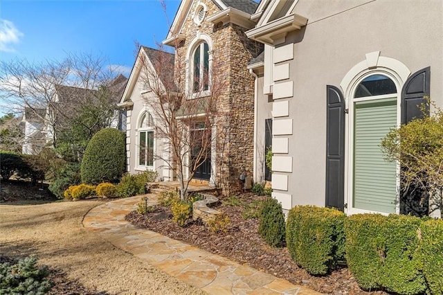 view of exterior entry featuring stone siding and stucco siding