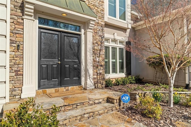 doorway to property with metal roof, stone siding, french doors, and a standing seam roof