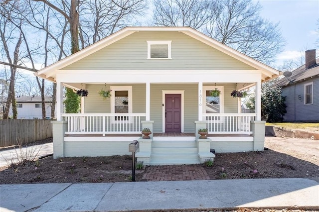 bungalow-style home with a porch and fence