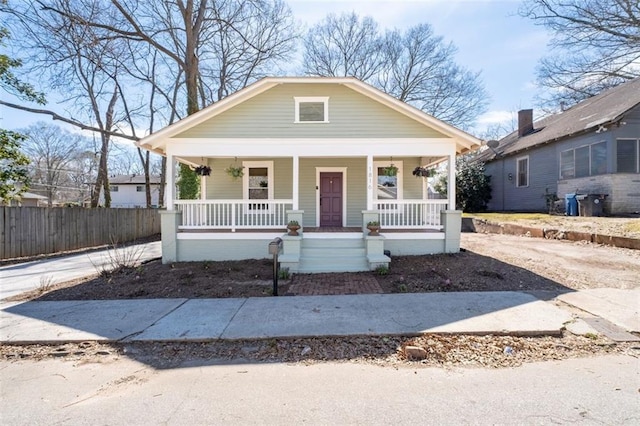 bungalow-style home with covered porch and fence