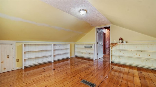 bonus room featuring a textured ceiling, wood-type flooring, and vaulted ceiling