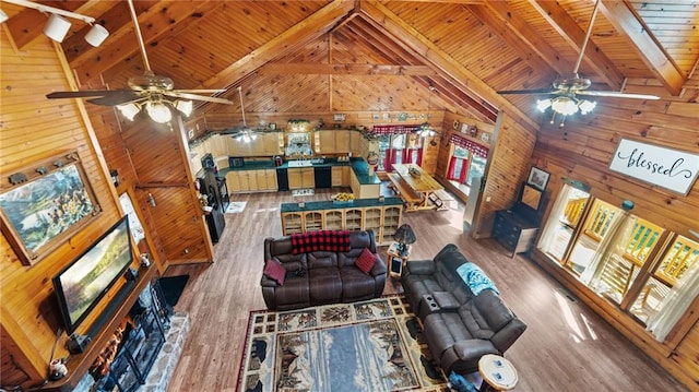 living room with wood walls, high vaulted ceiling, hardwood / wood-style flooring, ceiling fan, and beamed ceiling